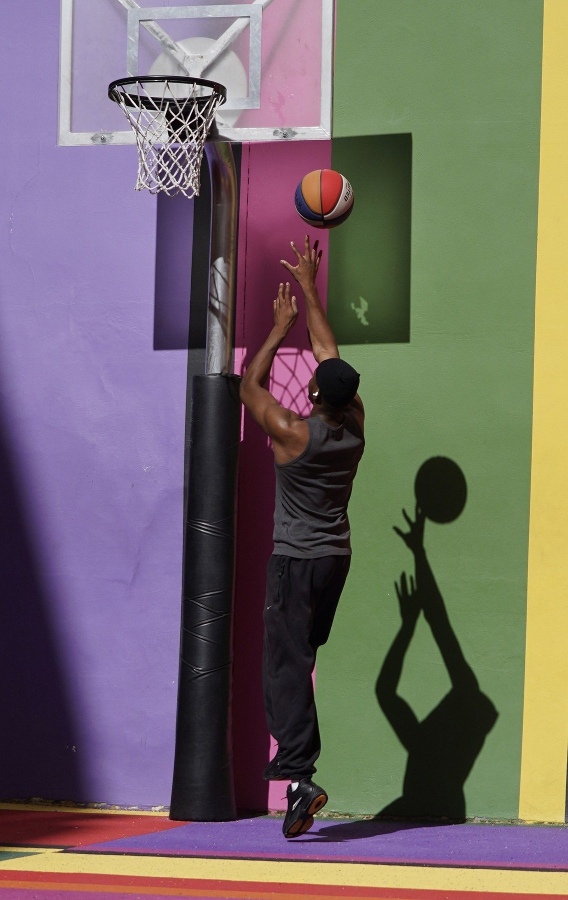 Basketball player and shadow on a colourful court in Paris