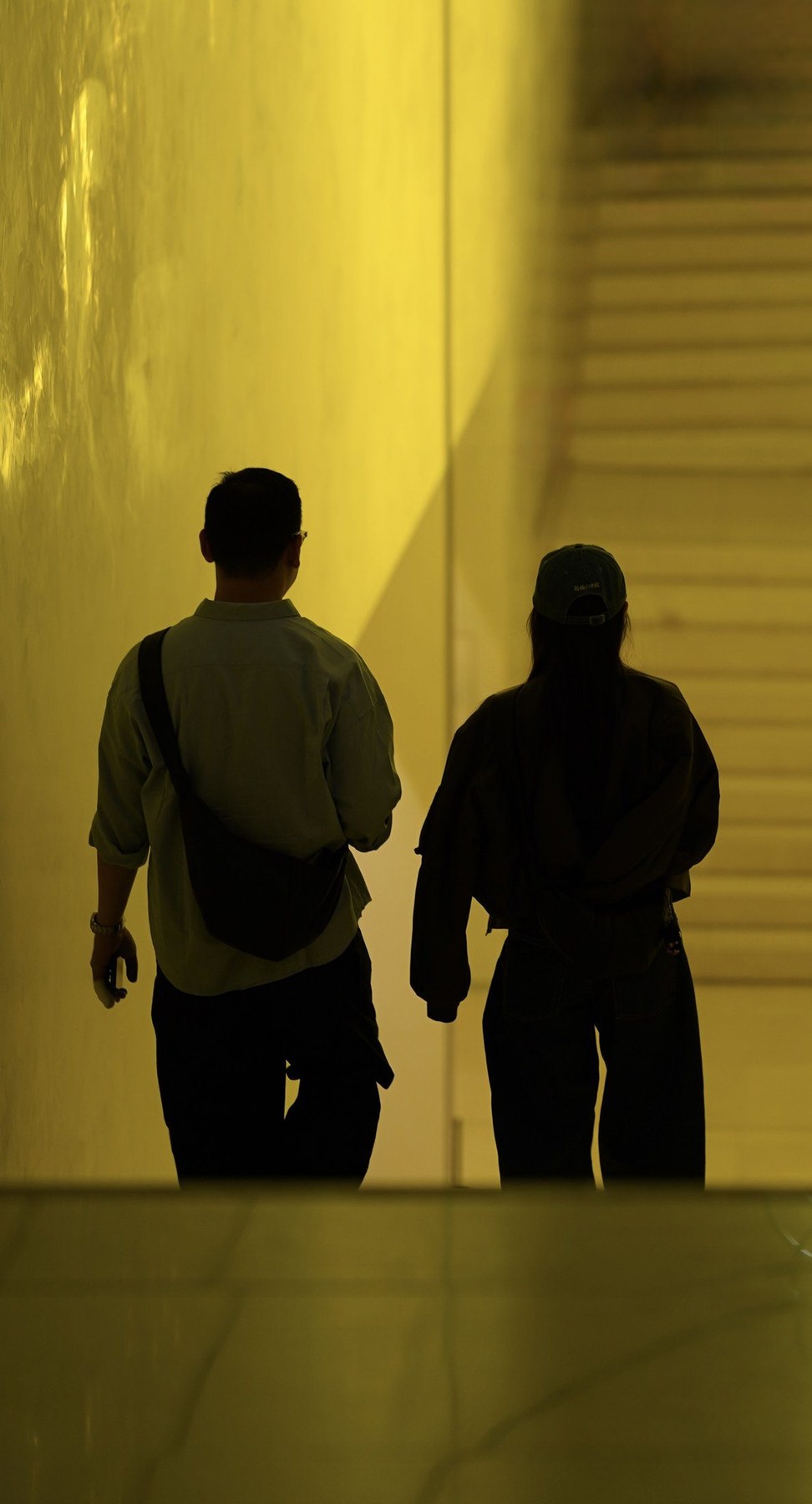 Two figures in a yellow architectural space