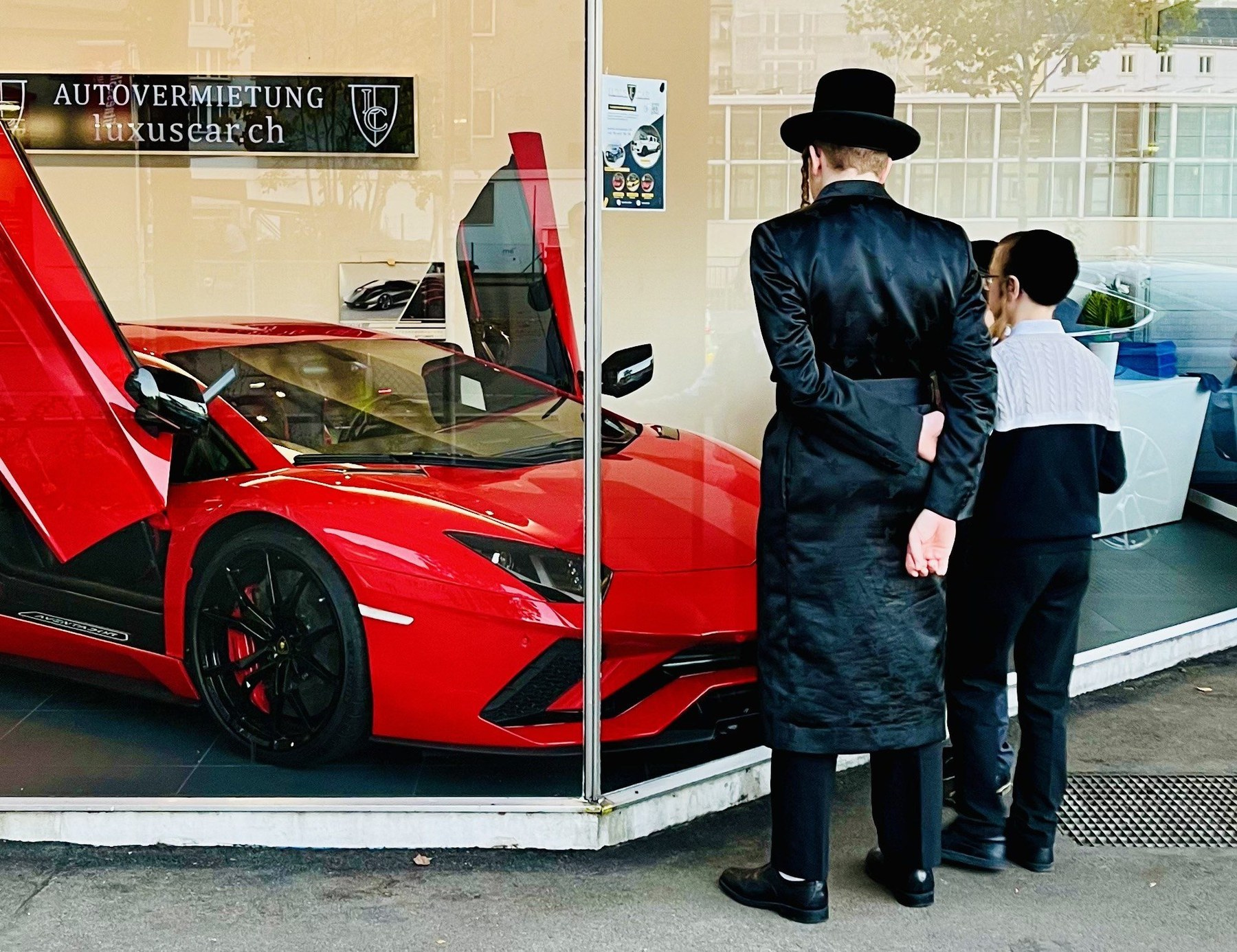 Two traditionally dressed men looking at a red sports car in Zurich